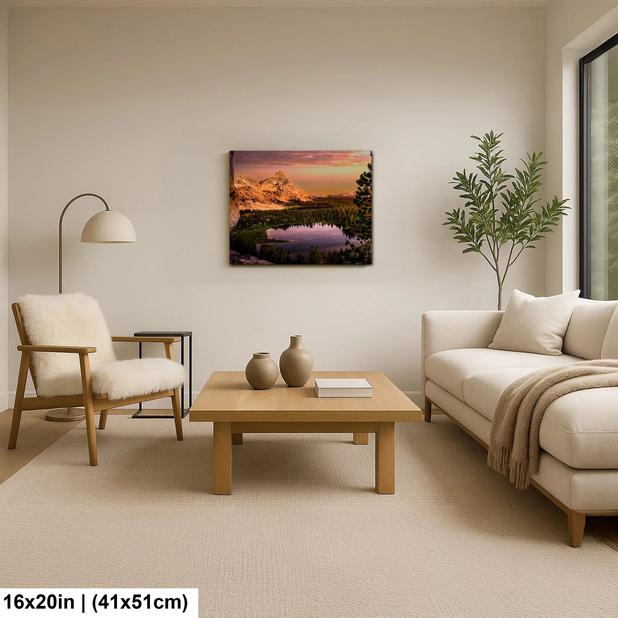 Cozy living room with minimalist furniture and a mountain landscape print above the sofa, featuring a peaceful lake surrounded by trees and soft sunset lighting.
