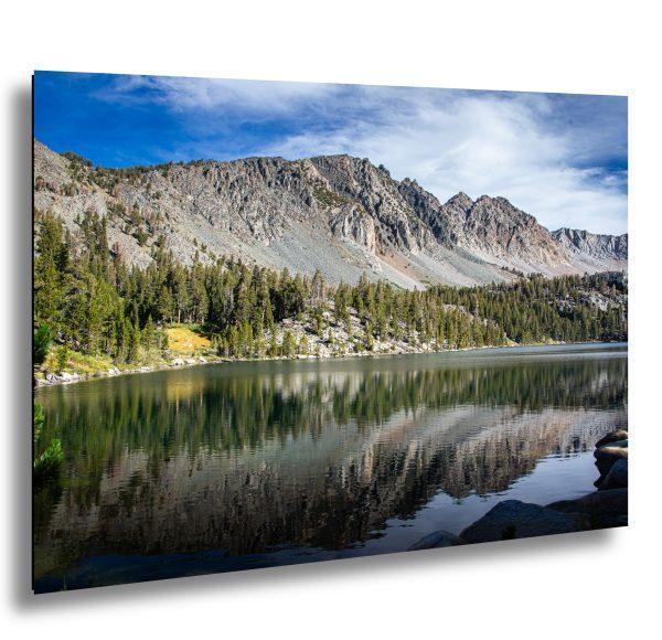 Alpine lake reflection with granite mountain peaks, conifer forest, and clear blue sky landscape photography.