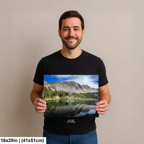 Man holding alpine lake reflection with granite mountain peaks and conifer forest landscape photography print.