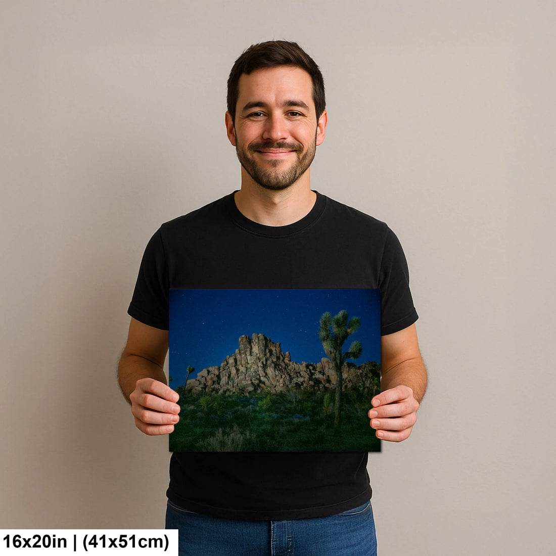 Photographer holding 16x20 inch Joshua Tree desert print on neutral background.