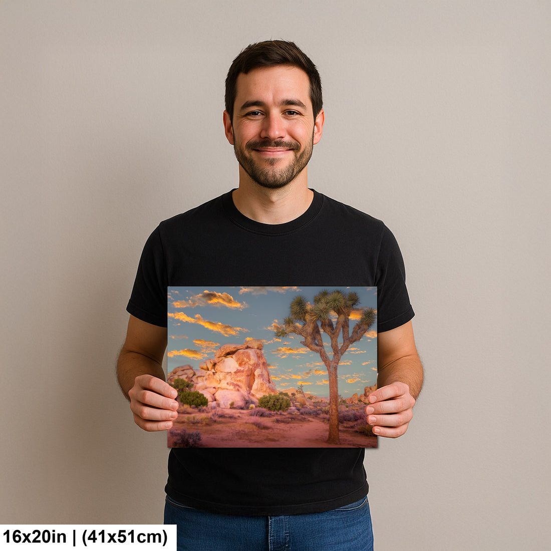 Man holding Joshua Tree National Park sunset photography print with pink boulders and orange sky landscape art.