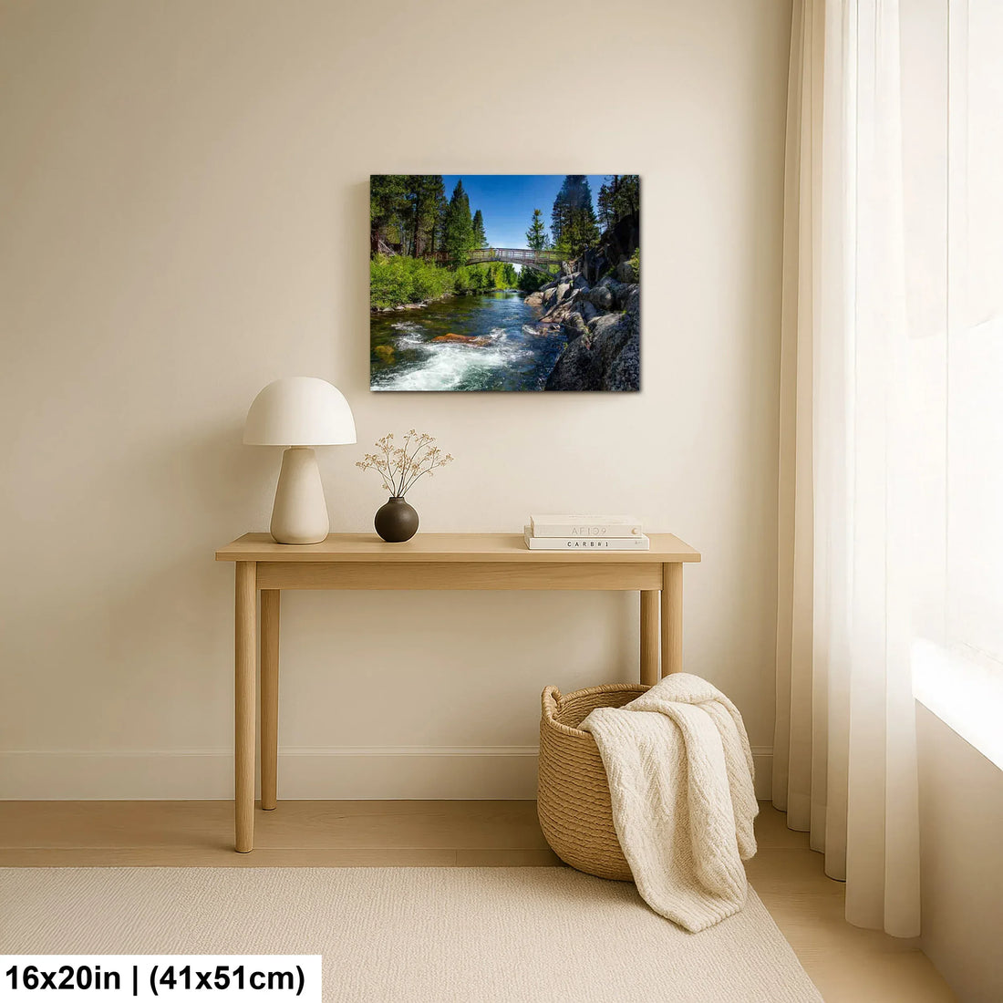 Alpine river and forest landscape canvas above wooden console table in minimalist home decor.
