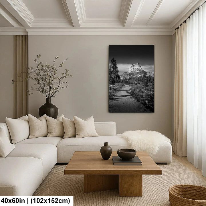 Black and white mountain peak and stream landscape canvas above cream sectional sofa in modern living room.