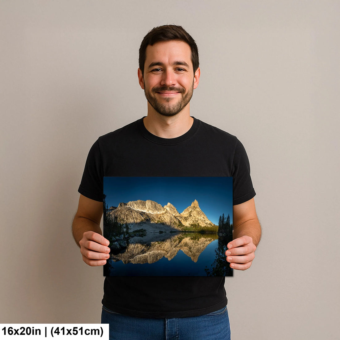 Man holding a 6x20 inch print of a mountain landscape with its reflection in a tranquil lake, smiling against a neutral background.