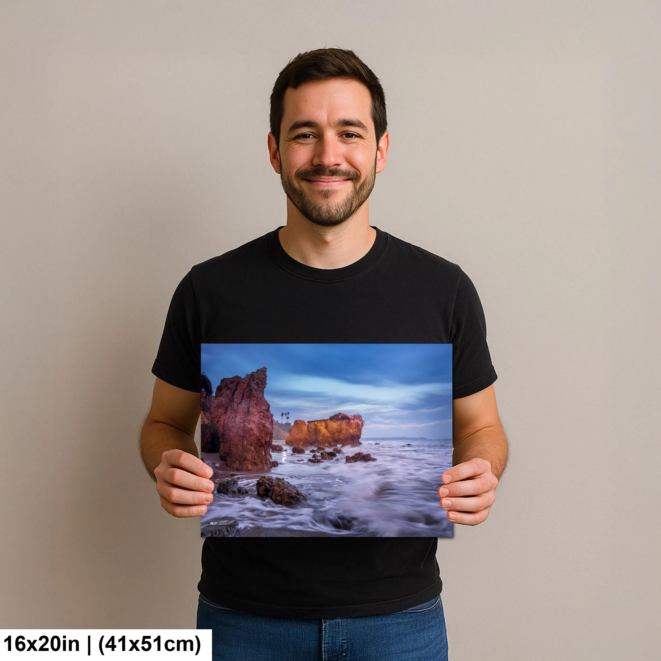 Photographer holding 16x20 inch El Matador Beach sunset seascape print on neutral background.