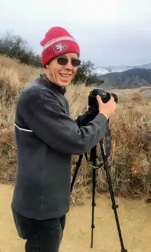 Landscape photographer with camera on tripod capturing desert scenery in California.